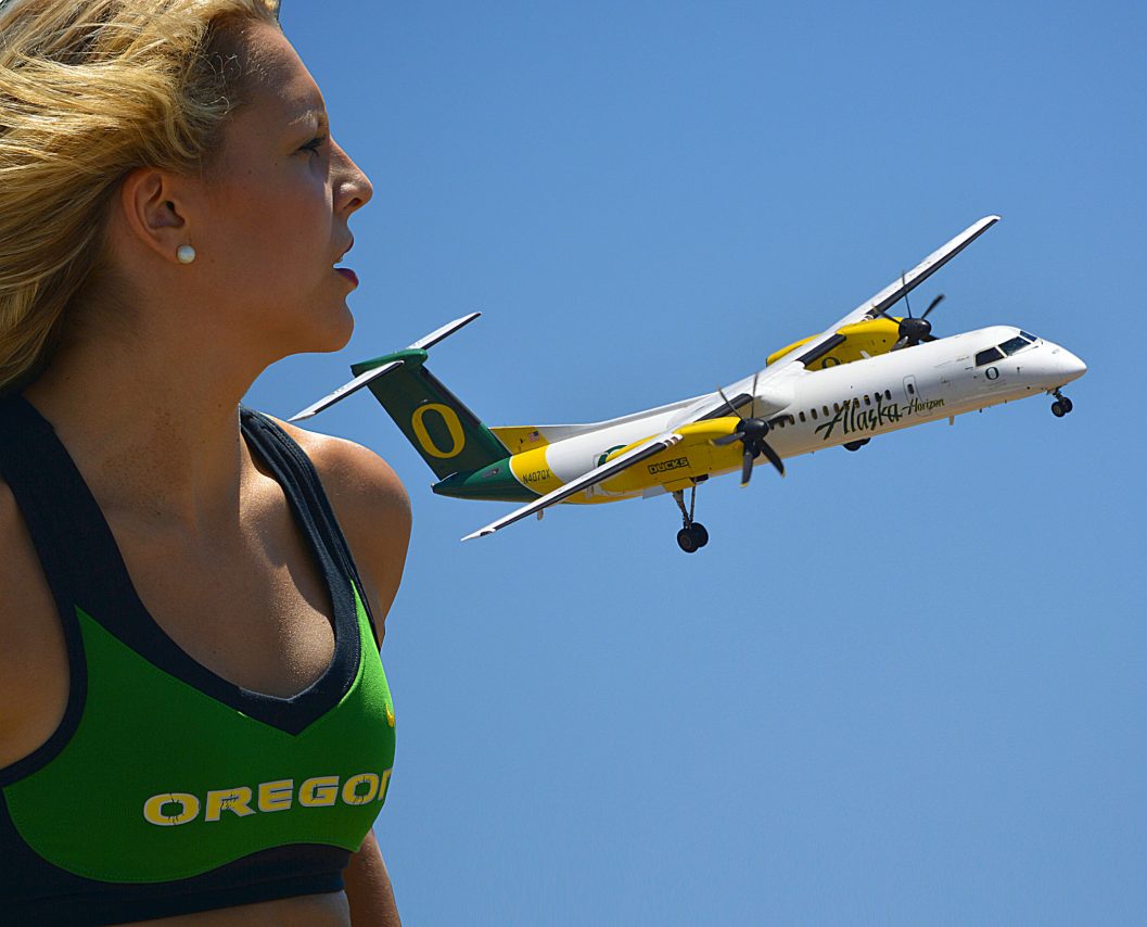 Oregon Ducks cheerleader watches an Alaska Airlines (Horizon) plane Q400 painted with the Ducks Logo and colors